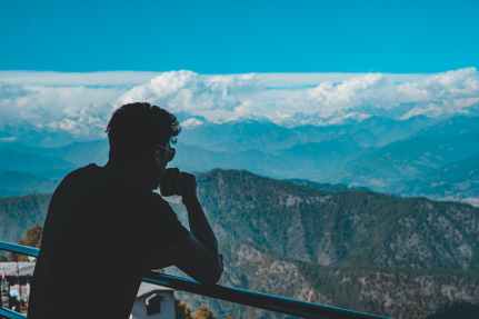 man in black shirt standing on top of mountain drinking coffee